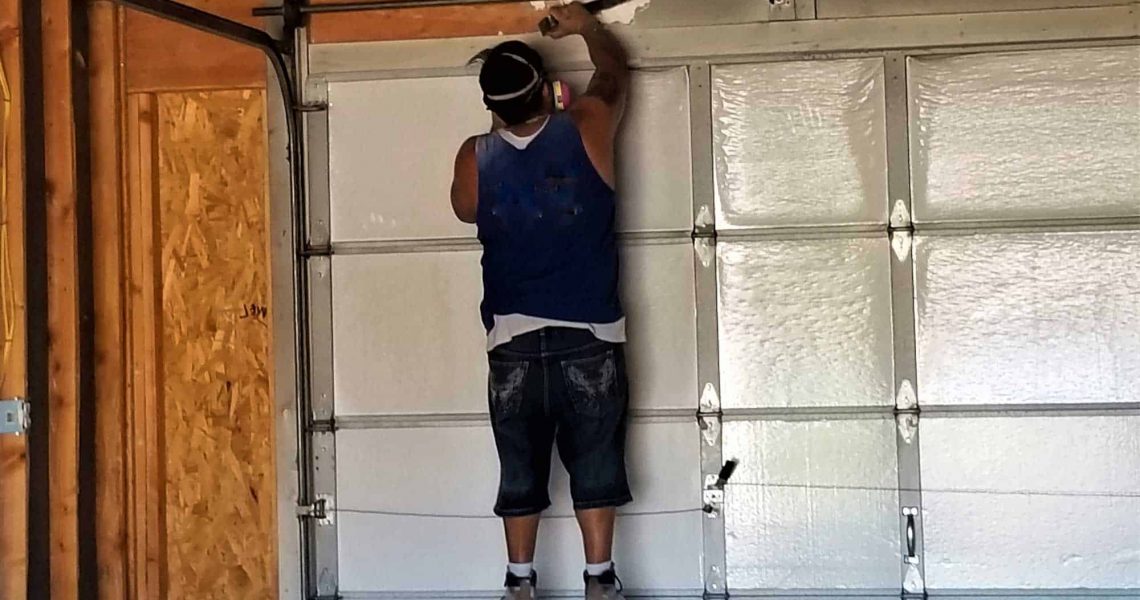 construction worker installing a rollup garage door with spring